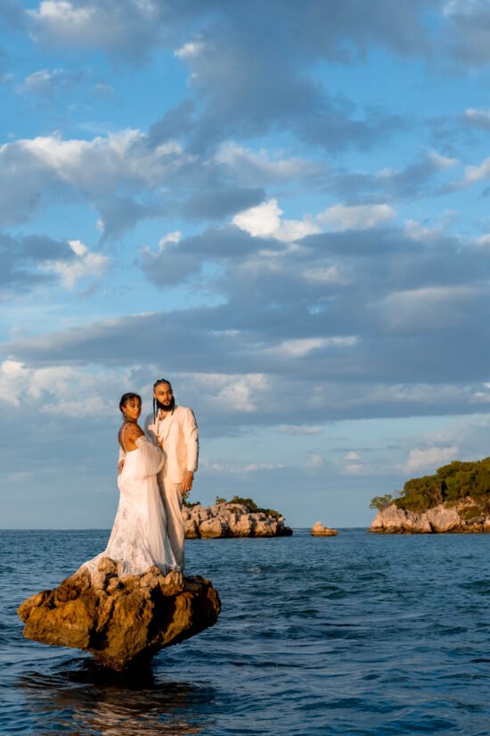 A visibe beautiful couple standing on some rocks in the middle of the sea